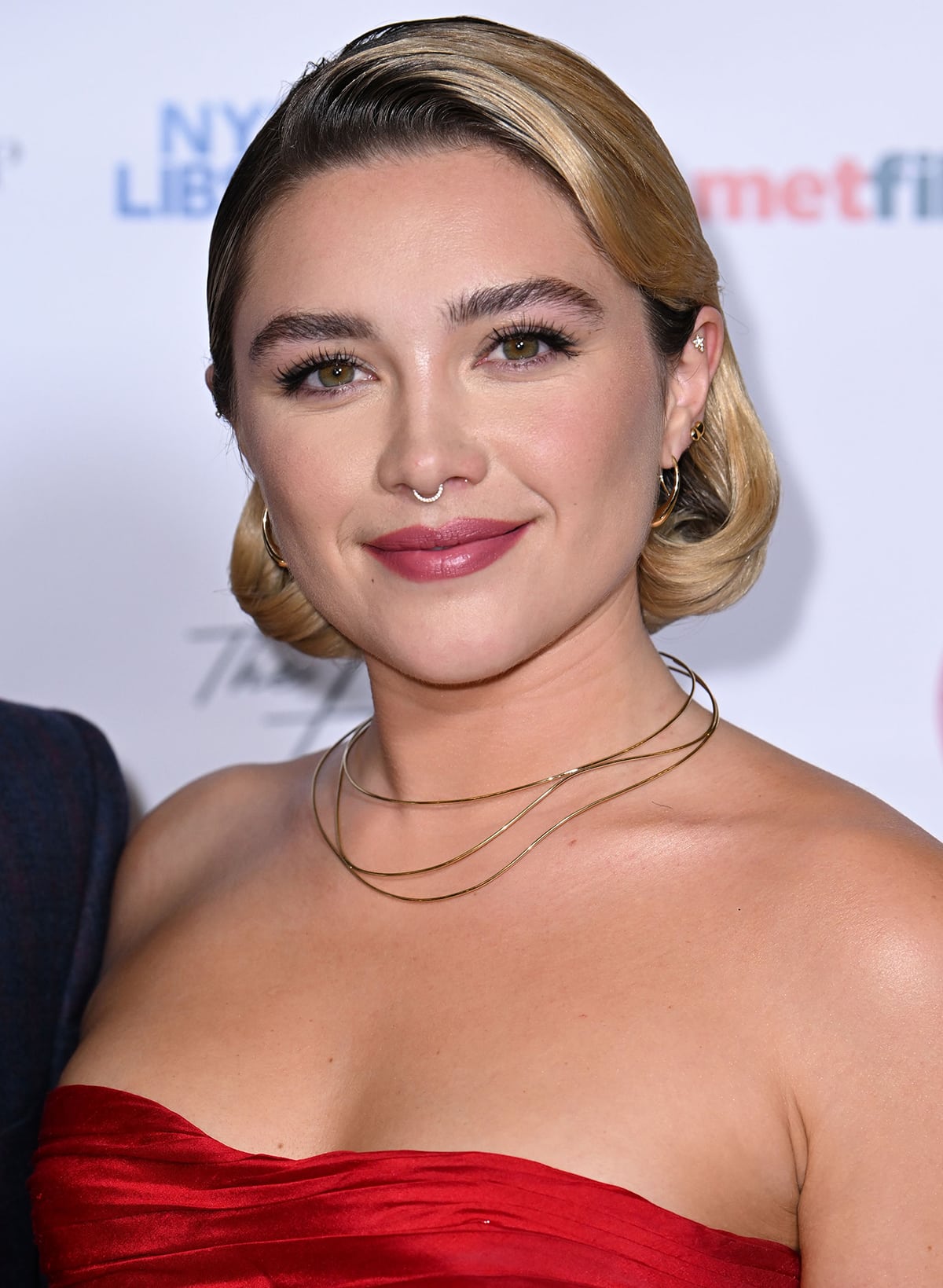 Florence Pugh completes the retro look with a side-swept short bob with tucked ends