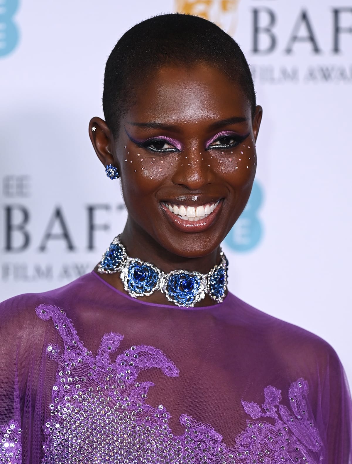 Jodie Turner-Smith wears trendy crystal freckles with metallic winged eyeliner and lilac eyeshadow to match her gown