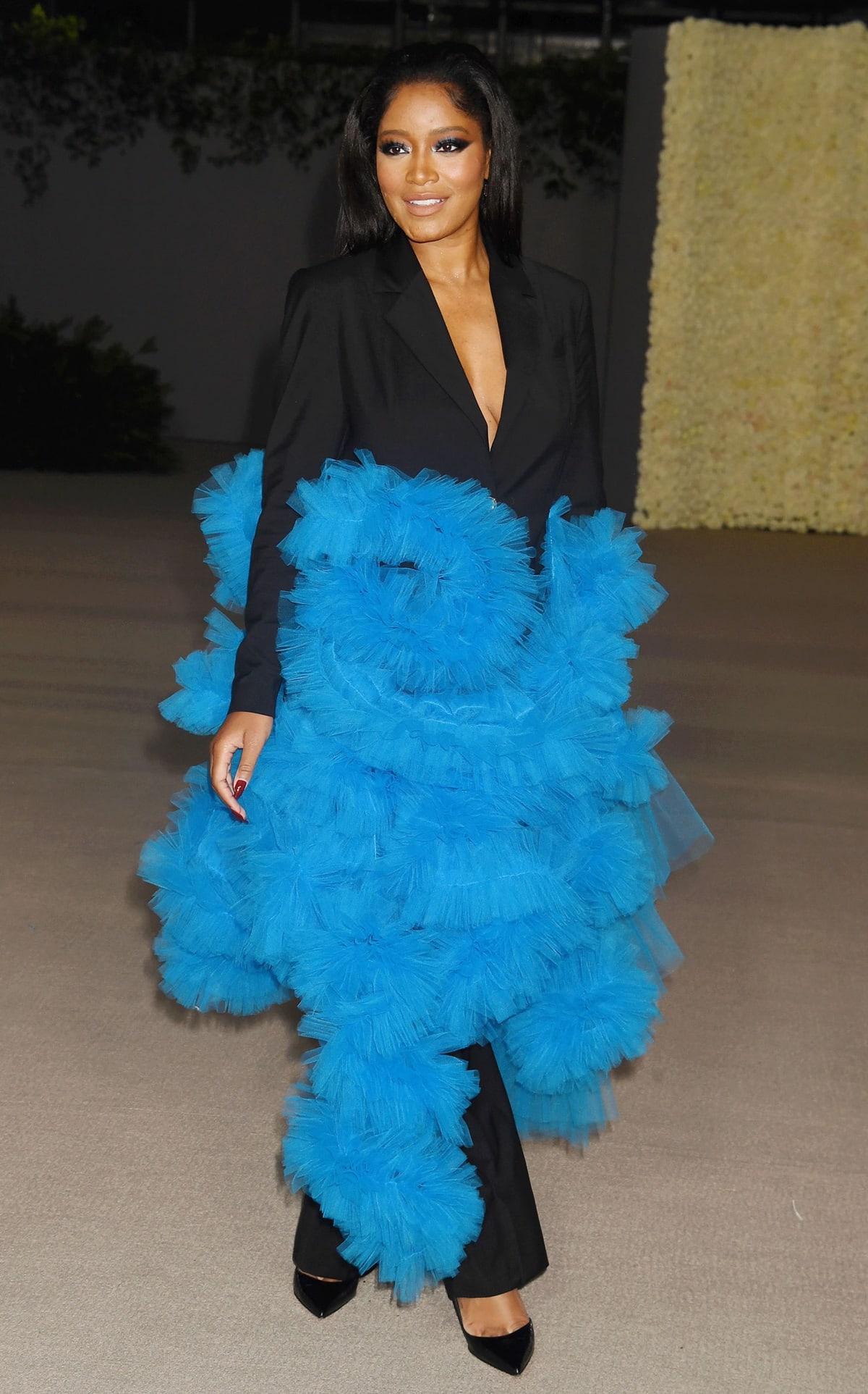 Keke Palmer in a strapless Saint Laurent dress featuring a bandeau of black feathers at the top, with flowing black fabric cascading around her body and ending in a wide hem of feathers, at the 2nd Annual Academy Museum Gala