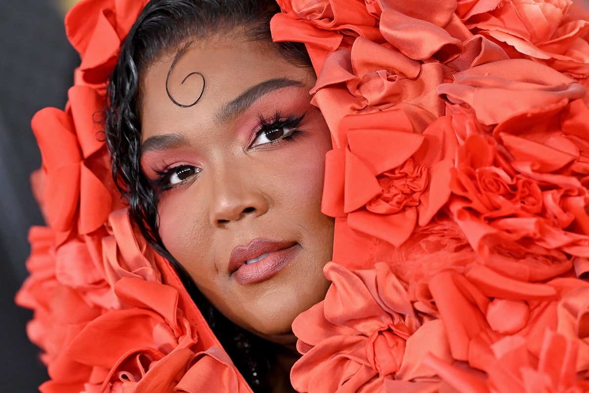 Lizzo's eye makeup and nails matched the orange-red gown, and she styled her hair in deep curls with one lock cascading down her forehead