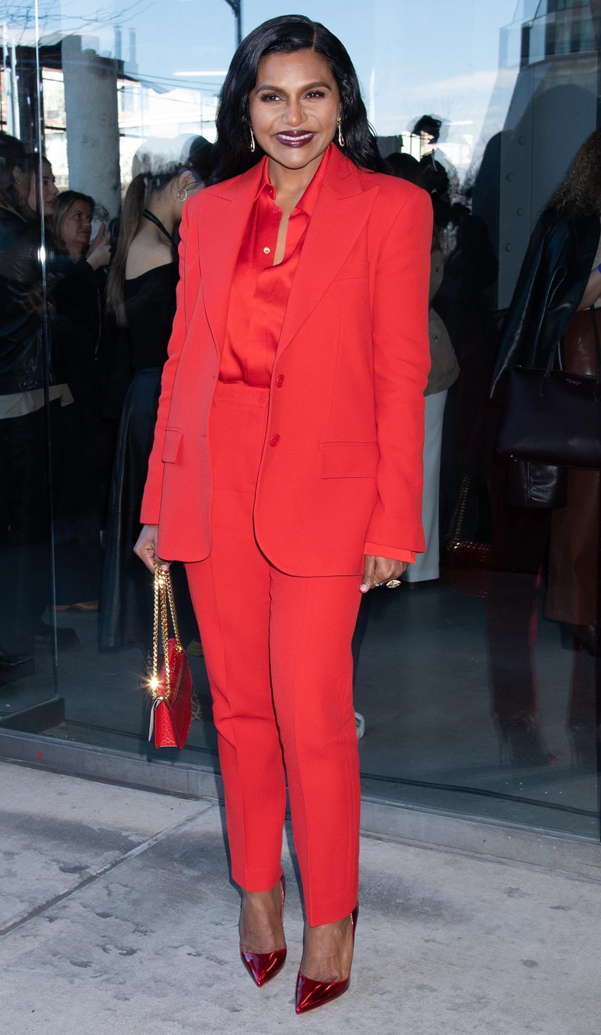 Mindy Kaling, in a bright red monochrome suit and sharp footwear, arrives for the Michael Kors fashion show