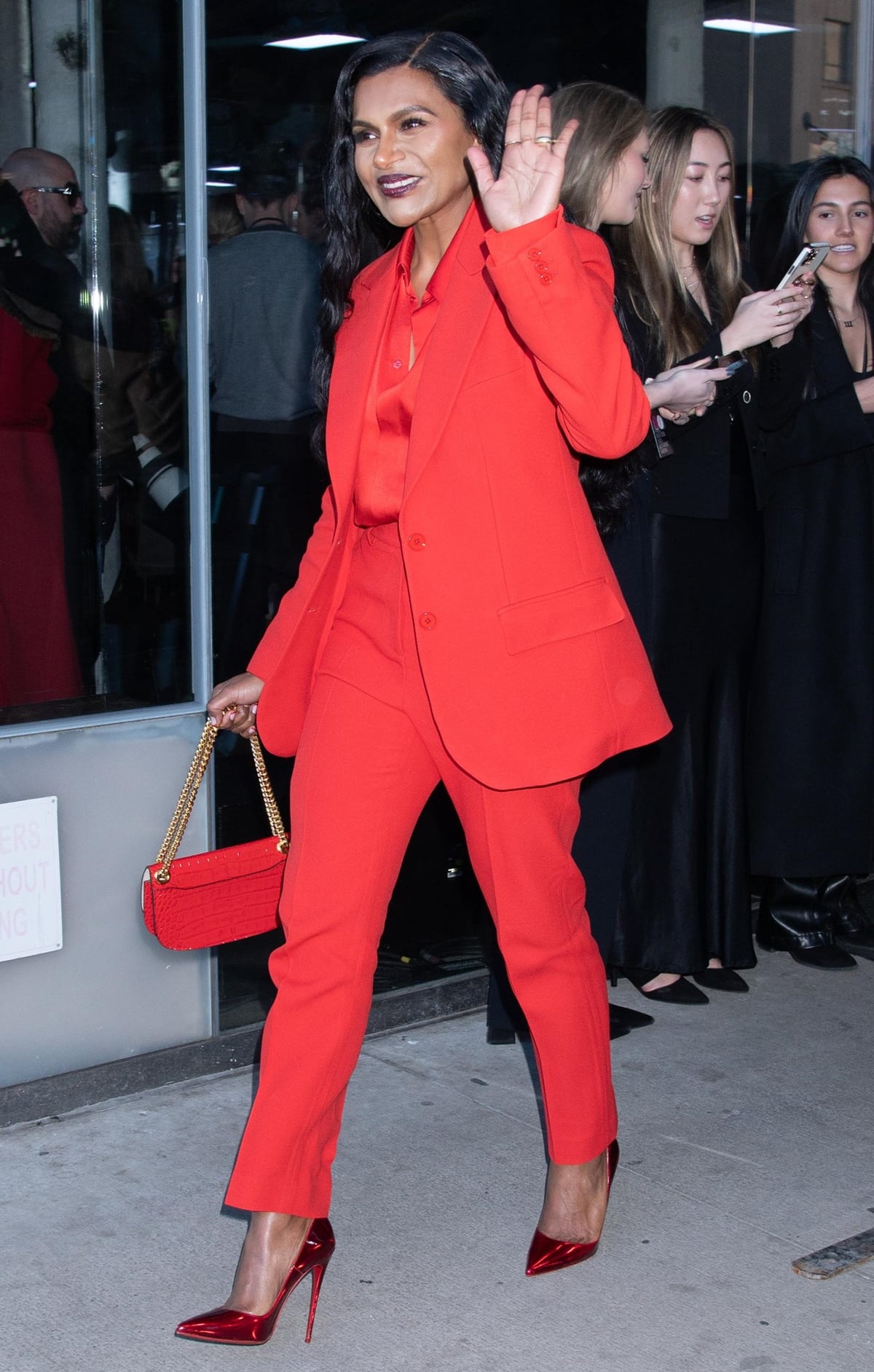 Mindy Kaling's look included a red tailored blazer layered over a satin button-down shirt tucked into matching crimson trousers, all tailored to perfection for a professional, business-forward vibe