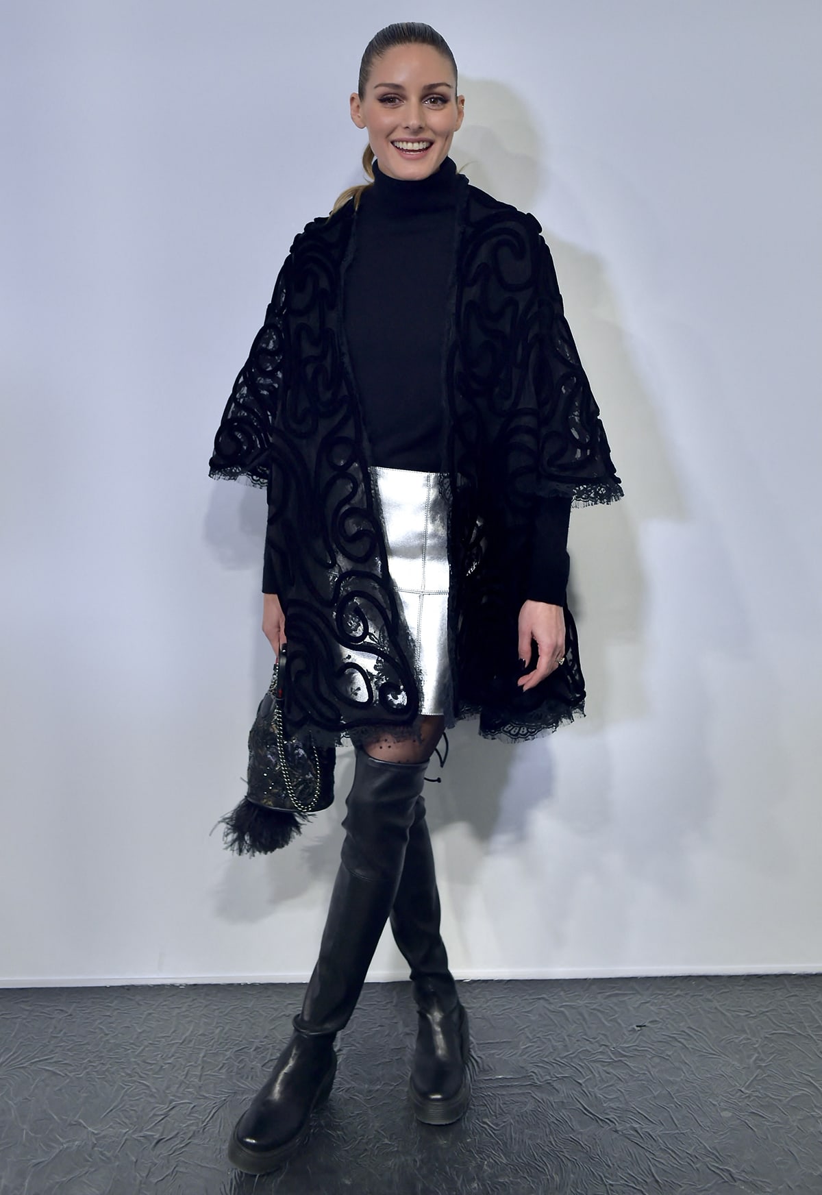 Olivia Palermo keeps a classy look in a black turtleneck sweater, a silver metallic mini skirt, and a lace jacket at Georges Chakra Paris Fashion Week show on January 24, 2023