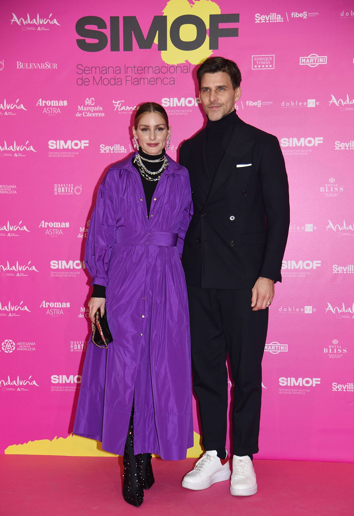 Olivia Palermo is a royal in a purple Antonio Garcia coat dress with a black turtleneck top and Stuart Weitzman's Ultrastuart Cosmic boots, while Johannes Huebl is handsome in a black double-breasted suit and white leather sneakers