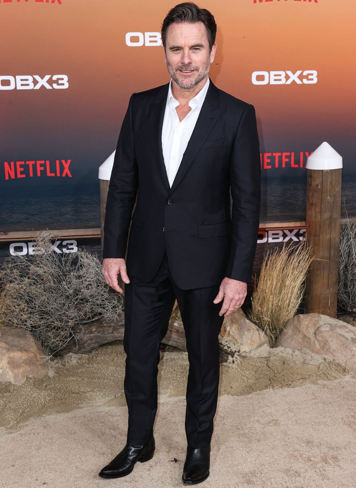 Charles Esten dressed up in a monochromatic suit and pointy-toe boots at the premiere of Netflix’s Outer Banks Season 3
