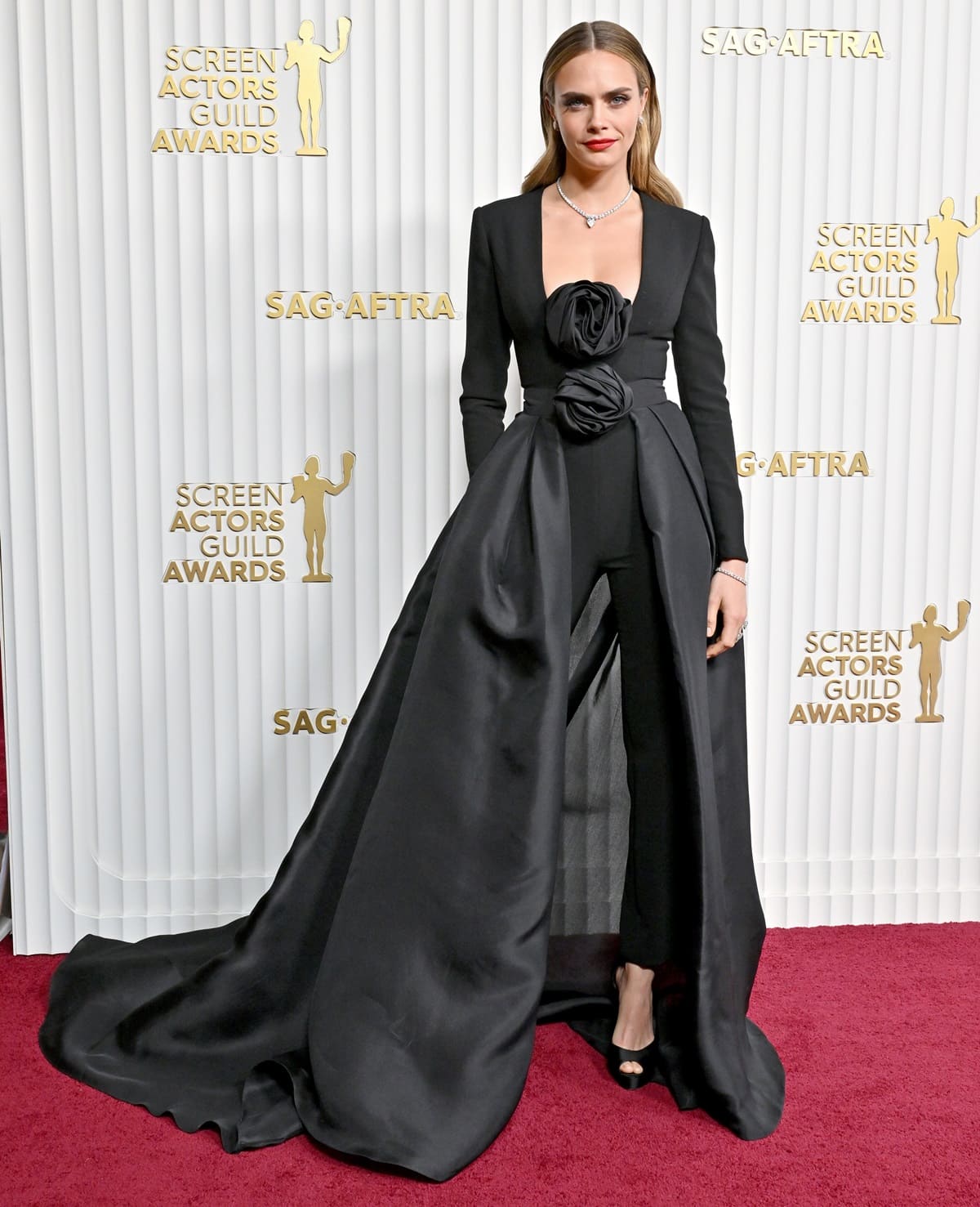 Cara Delevingne in a stunning Carolina Herrera jumpsuit featuring long sleeves and a plunging neckline adorned with oversized rosette appliqués at the 29th Annual Screen Actors Guild Awards