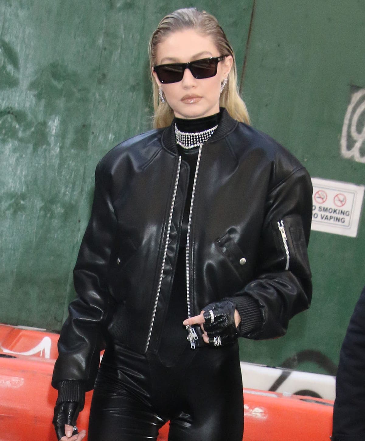 Gigi Hadid completes her biker look with boxy sunnies, fingerless biker gloves, and leather stiletto boots