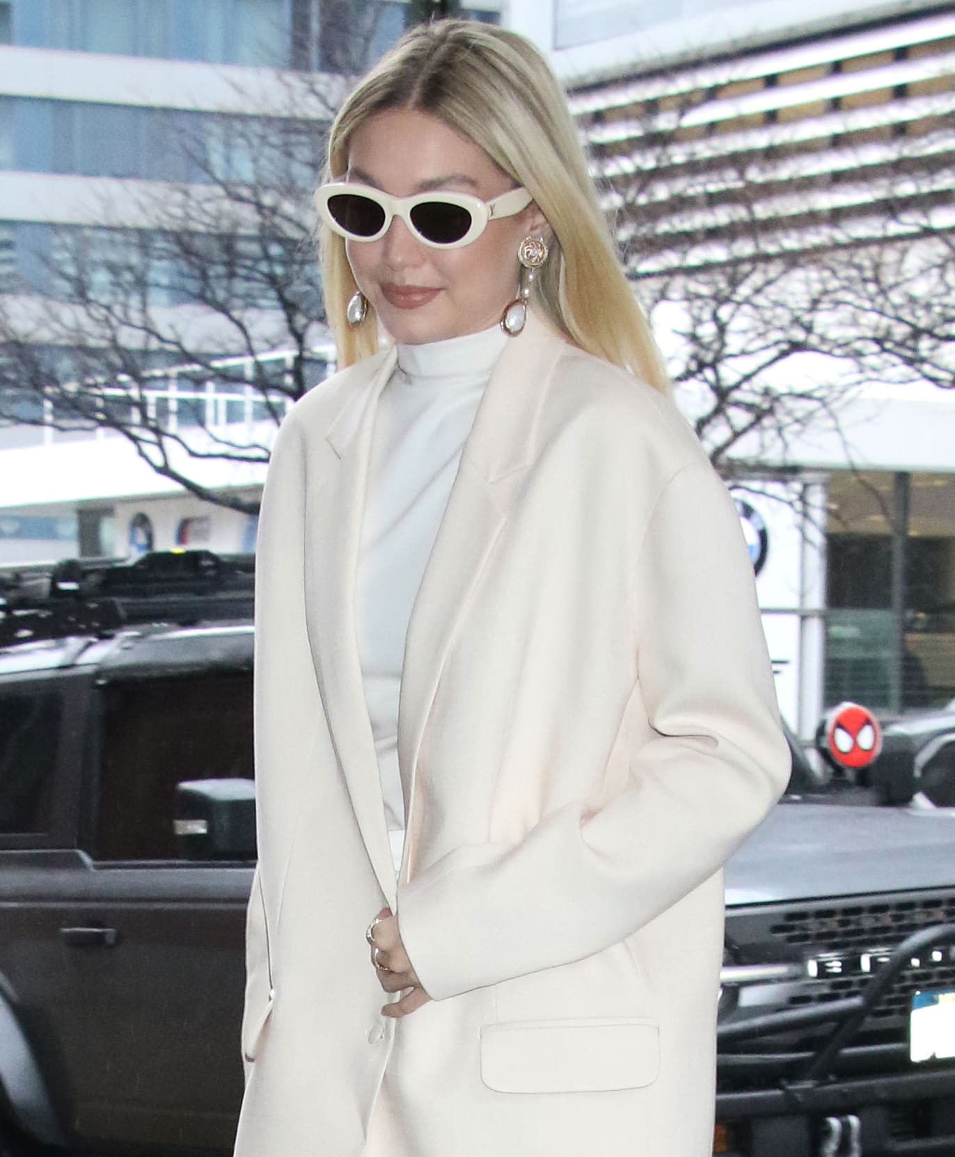 Gigi Hadid completes her ethereal white look with retro-framed oval sunglasses and Lionheart jewelry