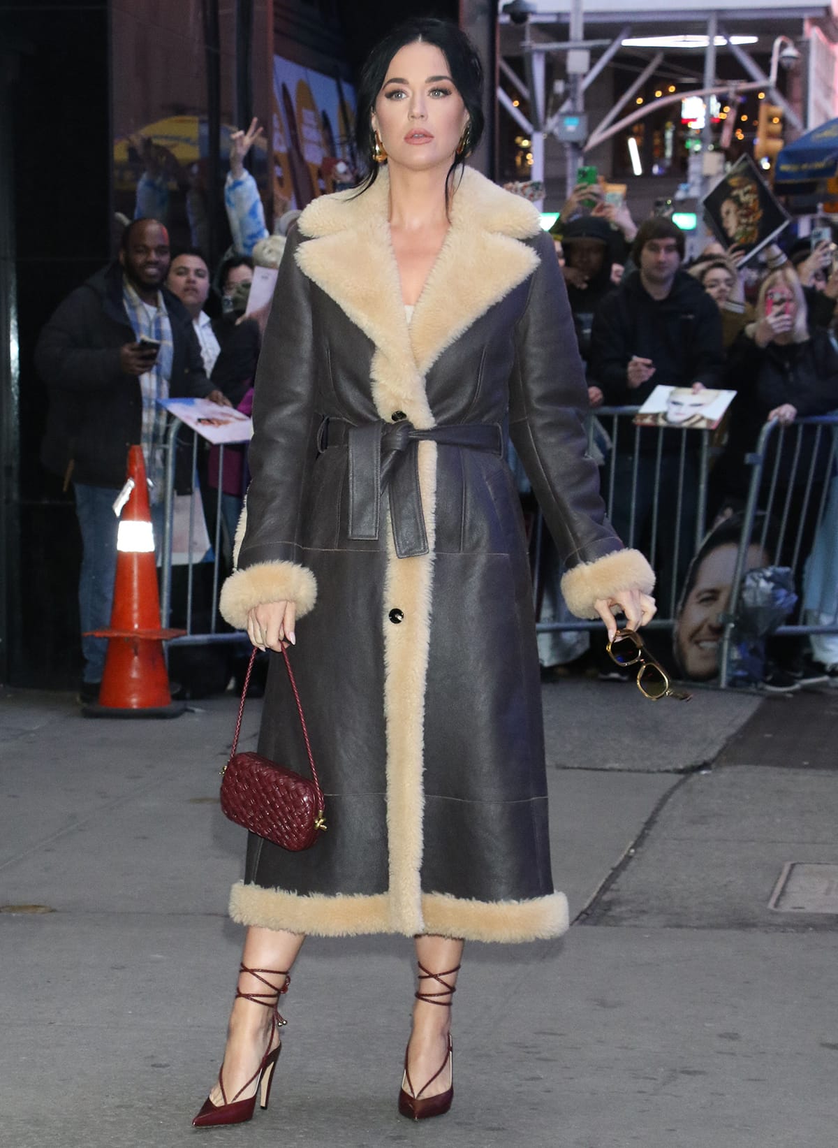 Katy Perry kicks off her day with a guest appearance on Good Morning America wearing a Bottega Veneta brown leather shearling-trimmed coat and a burgundy mini dress underneath