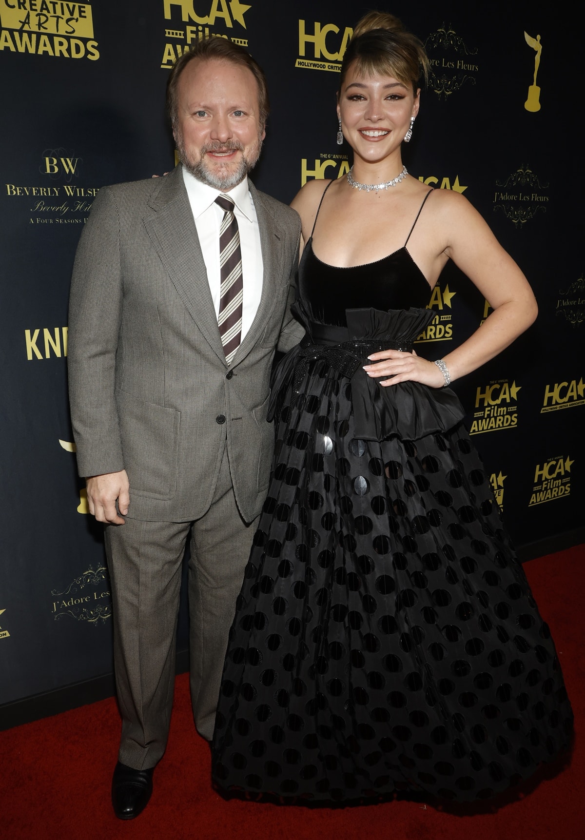Joined by Golden Onion: A Knives Out Mystery director Rian Johnson, Madelyn Cline turned heads in a stunning black dress with a low-cut neckline and spaghetti straps that flaunted her toned arms at the Hollywood Critics Association's 2023 HCA Film Awards