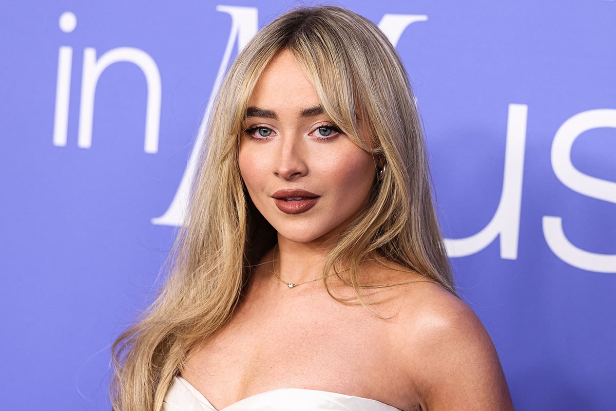 Sabrina Carpenter keeps a sexy look by styling her blonde hair in loose waves and wearing cranberry lip color
