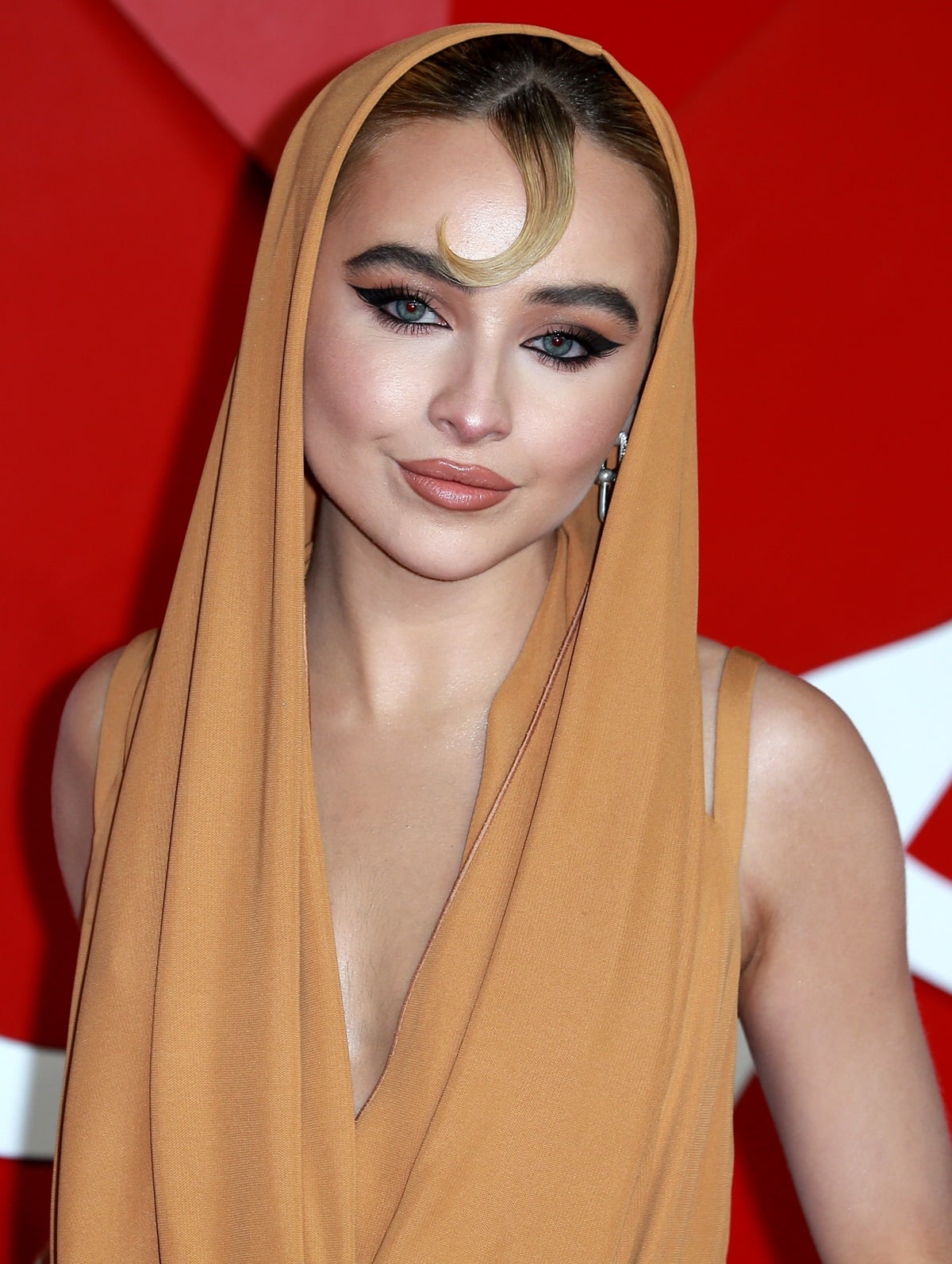 Sabrina Carpenter in a hooded beige jumpsuit with an edgy hairdo at The Fashion Awards 2022