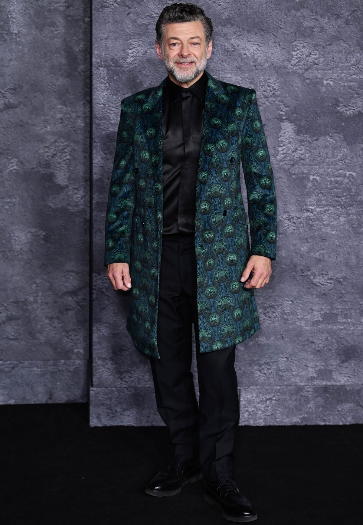 Andy Serkis makes a bold statement in a patterned emerald overcoat layered over a sleek black ensemble at the world premiere of Luther: The Fallen Sun