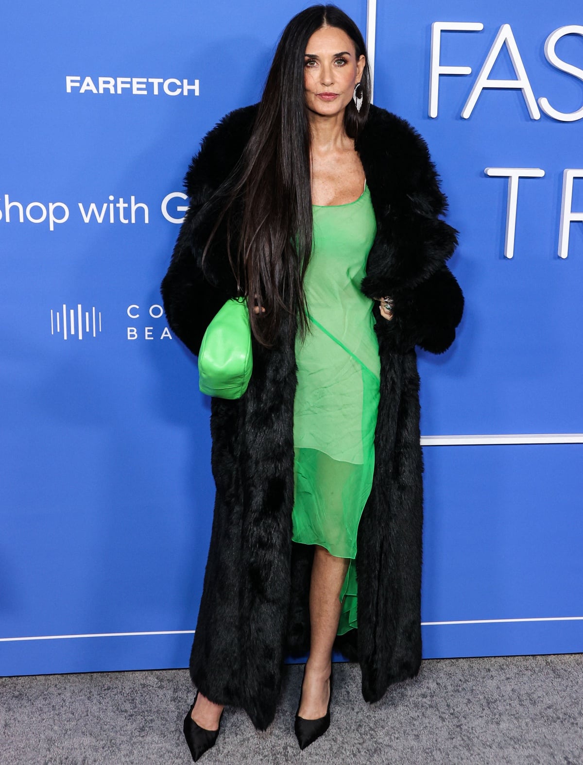 Demi Moore looking stunning in a lime green Givenchy Fall/Winter 2023 dress with a black fur coat and Le Silla heels