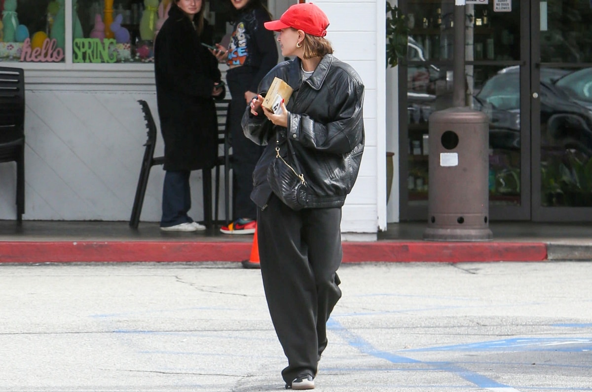 Hailey Biber dressed down in slouchy pants and an oversized leather jacket with Adidas sneakers