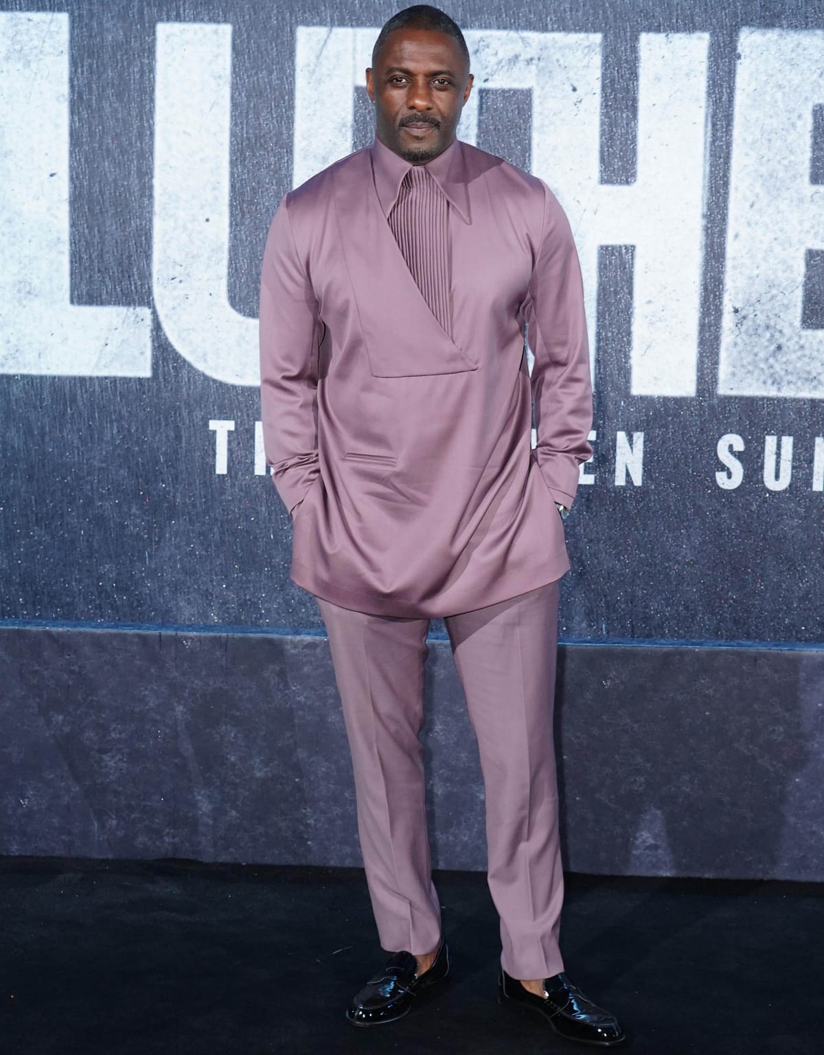 Idris Elba exudes effortless elegance in a modern mauve satin suit paired with sleek black Christian Louboutin patent loafers at the premiere of Luther: The Fallen Sun