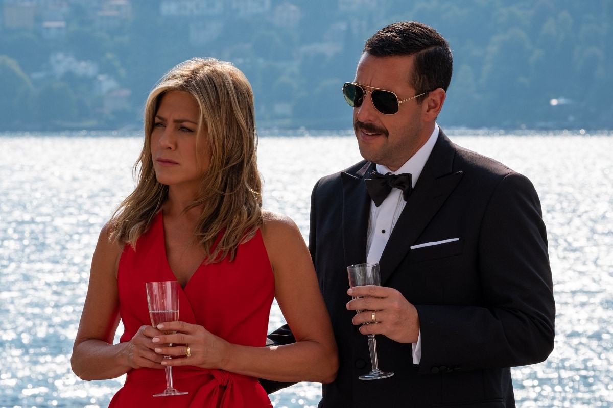 Jennifer Aniston and Adam Sandler share a moment in Murder Mystery 2, looking sharp in glamorous outfits during an elegant event by the water