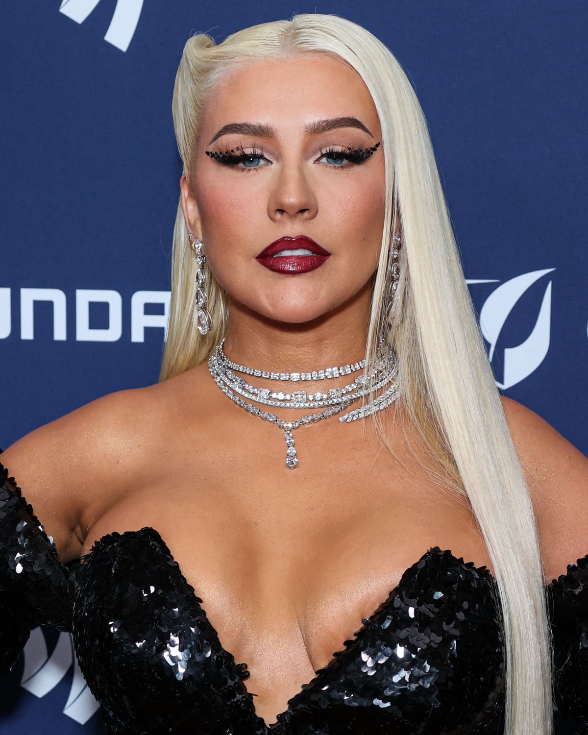 Christina Aguilera wore her hair down, with the right side elegantly pinned back to showcase her sparkling chandelier earrings and layers of choker necklaces