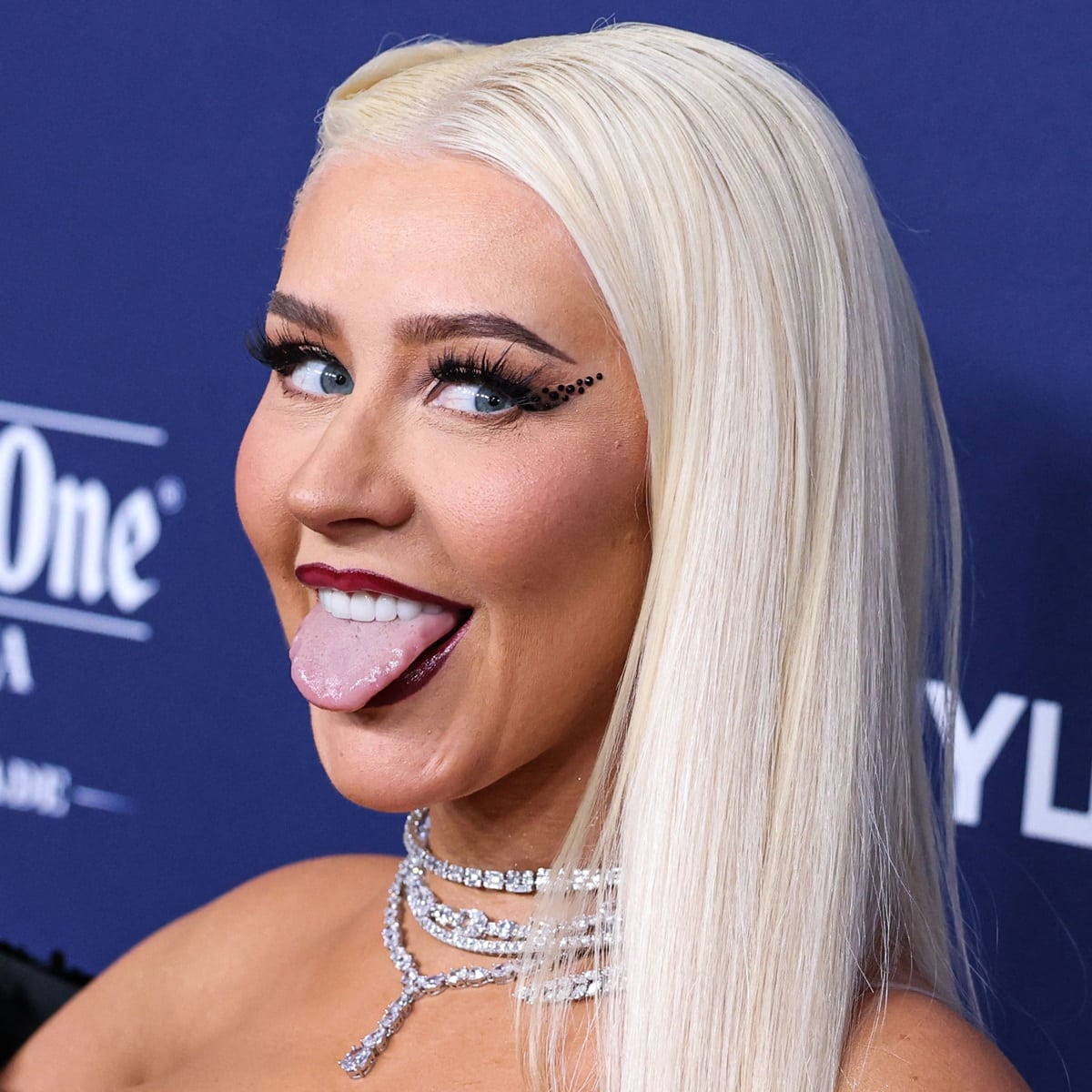 Christina Aguilera shows off her tongue at the GLAAD Media Awards with bold berry-red lips and thick winged eyeliner perfectly complemented her ensemble