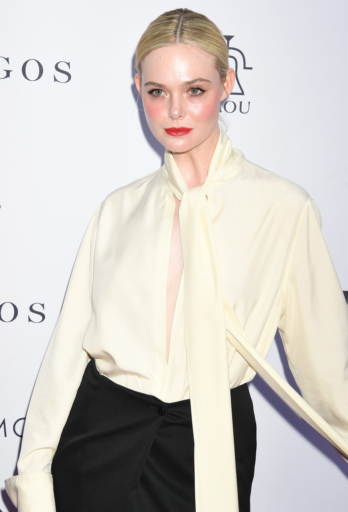Elle Fanning accentuates her blue eyes with cat-eye makeup and wears her platinum blonde hair in a neat updo