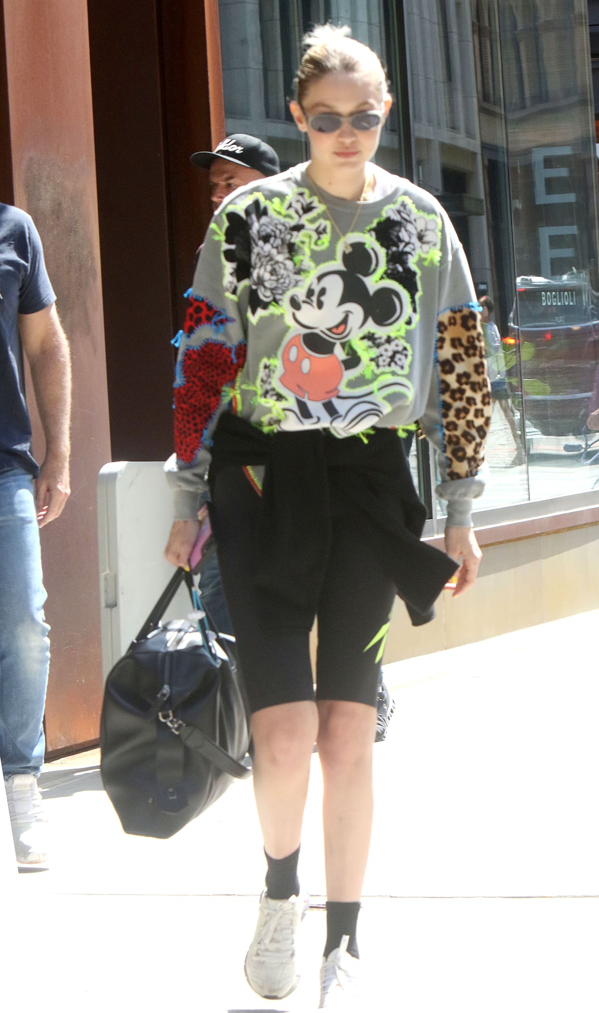 Gigi Hadid heads to Florida in a Mickey Mouse sweater, biker shorts, and athletic shoes on April 21, 2023