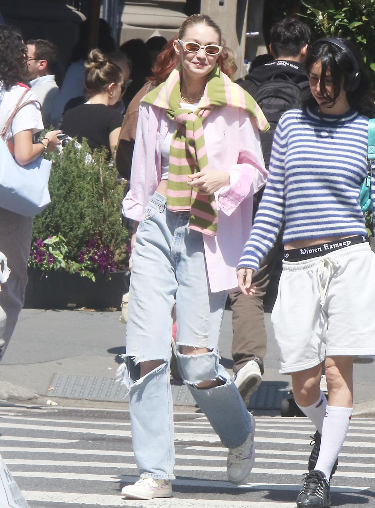 Gigi Hadid out and about in NYC with Leah McCarthy in a Polo Ralph Lauren pink striped shirt, Guest in Residence sweater, and Danielle Guizio baggy jeans on April 20, 2023