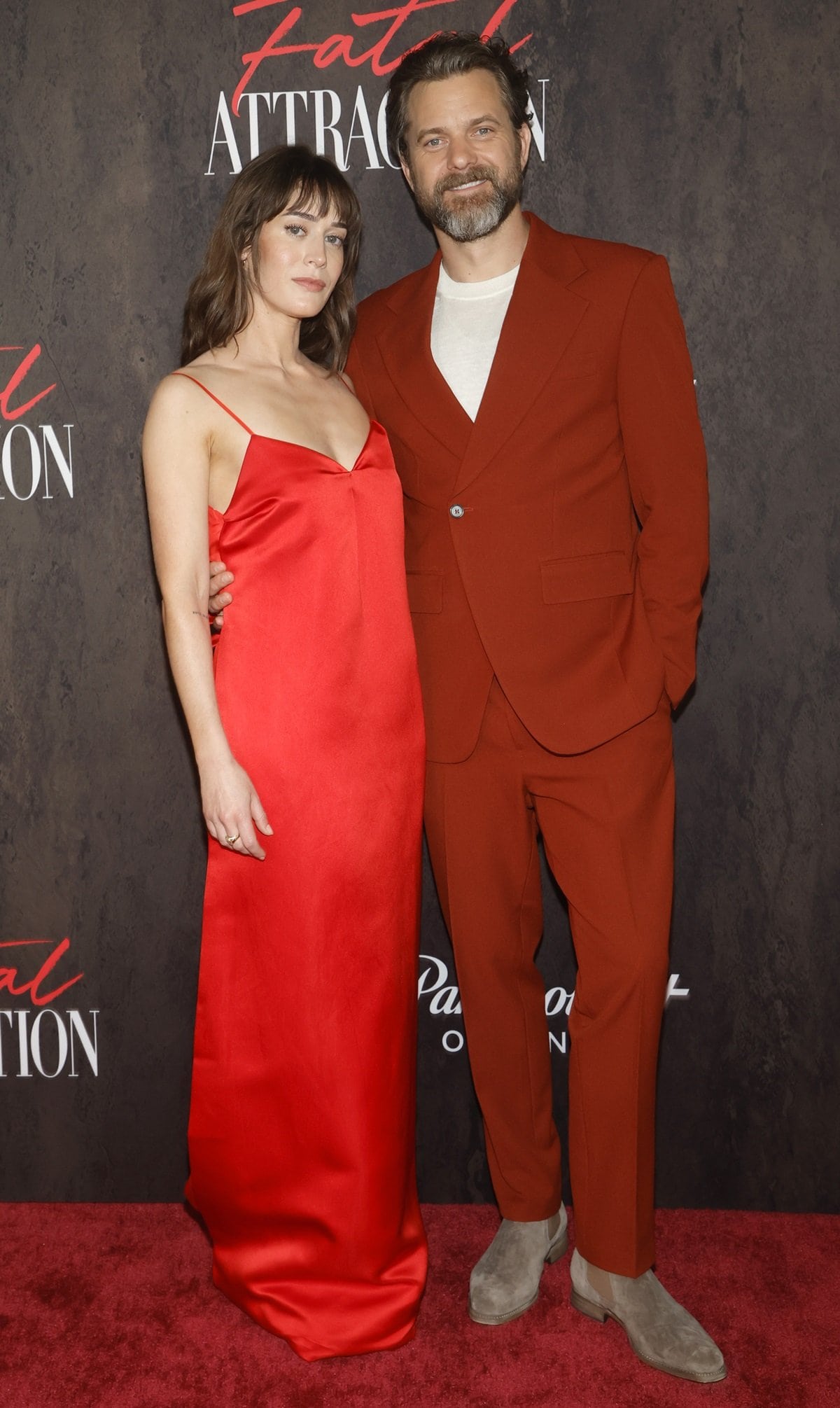Lizzy Caplan wore a red silk Prada dress, and Joshua Jackson coordinated with her by wearing a red suit at the star-studded Fatal Attraction premiere in Los Angeles on April 24, 2023