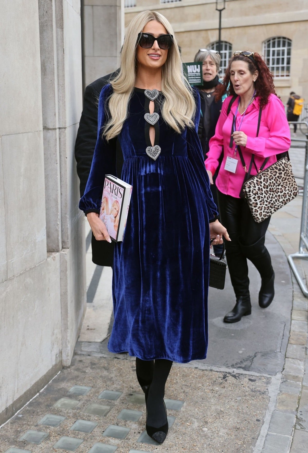 Paris Hilton wears a blue velvet Saloni Camille heart embellished dress with Sarah Flint Perfect pumps and a Self-Portrait croc mini bow bag to promote her memoir in London