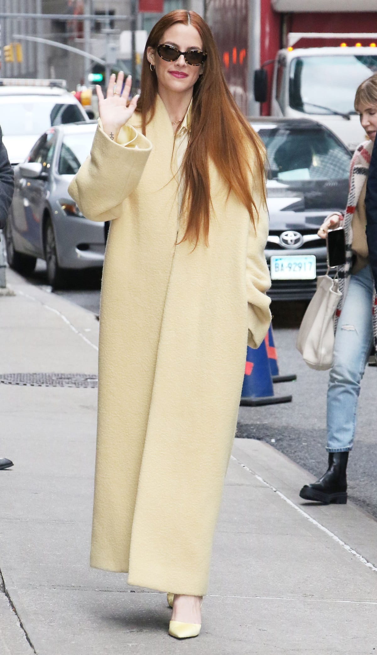 Riley Keough arrives for a taping of The Drew Barrymore Show in a yellow The Row Ceren brushed alpaca-blend coat paired with Khaite x Oliver Peoples 1969C sunglasses and Charles & Keith Sepatu pumps
