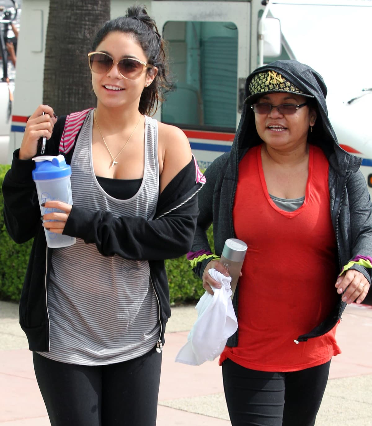 Vanessa Hudgens and her mother, Gina Guangco, keep it casual in sporty outfits as they head out, with Vanessa in a striped tank top and black leggings, while Gina opts for a red tee and black hoodie