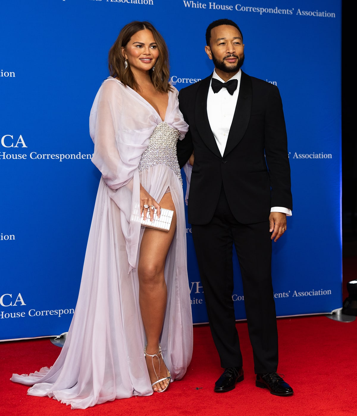 Chrissy Teigen showcases her legs in a Georges Hobeika sheer ruffled gown and Aquazzura heels as she poses alongside her husband John Legend at the White House Correspondents' Dinner at the Washington Hilton Hotel on April 29, 2023