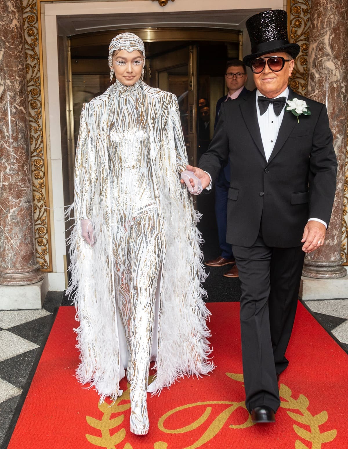 Gigi Hadid, wearing a striking silver jumpsuit designed by Michael Kors for the 2019 Met Gala, leaves her Pierre Hotel in New York City with fashion designer Michael Kors