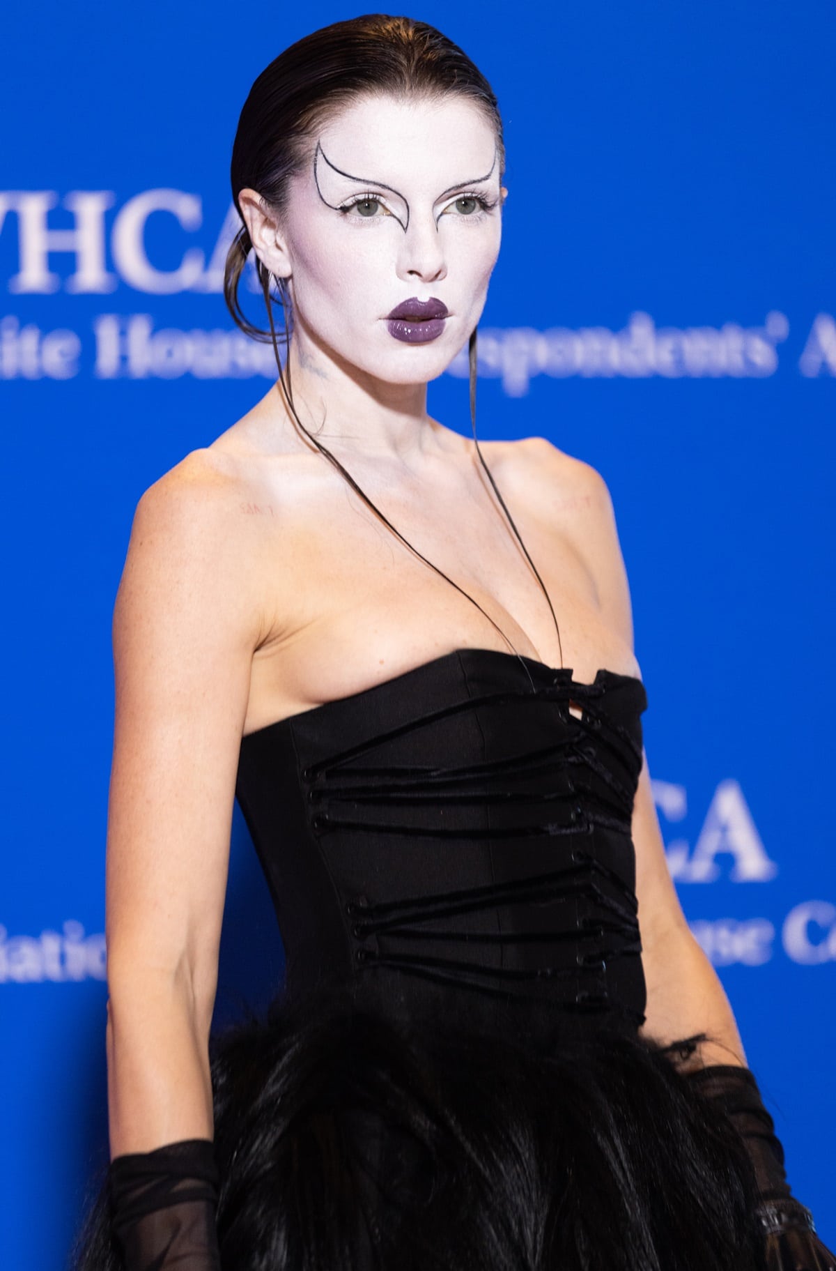 Julia Fox's dark brunette locks were styled into a messy updo, while her makeup featured a vampy spin on Rococo glamour, with white foundation, graphic eyeliner, and a glossy violet lip