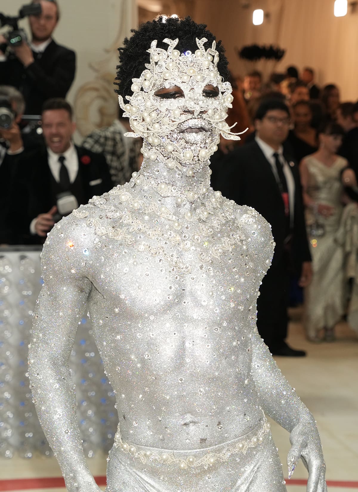 Lil Nas X wears an intricately embellished Venetian-style mask with silver, pearls, rhinestones, and glittering whiskers