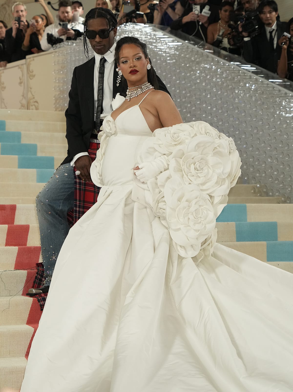 Rihanna showcases her growing baby bump in the white gown that features a rosette-adorned plunging neckline and thin spaghetti straps