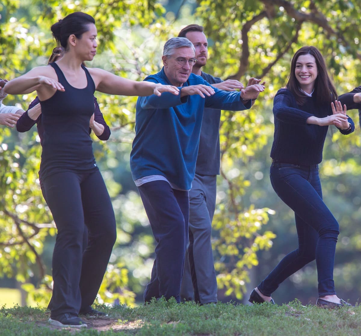 Robert De Niro, Anne Hathaway, and Tiffany Chen practice Tai Chi in a park in the 2015 American buddy comedy-drama film The Intern