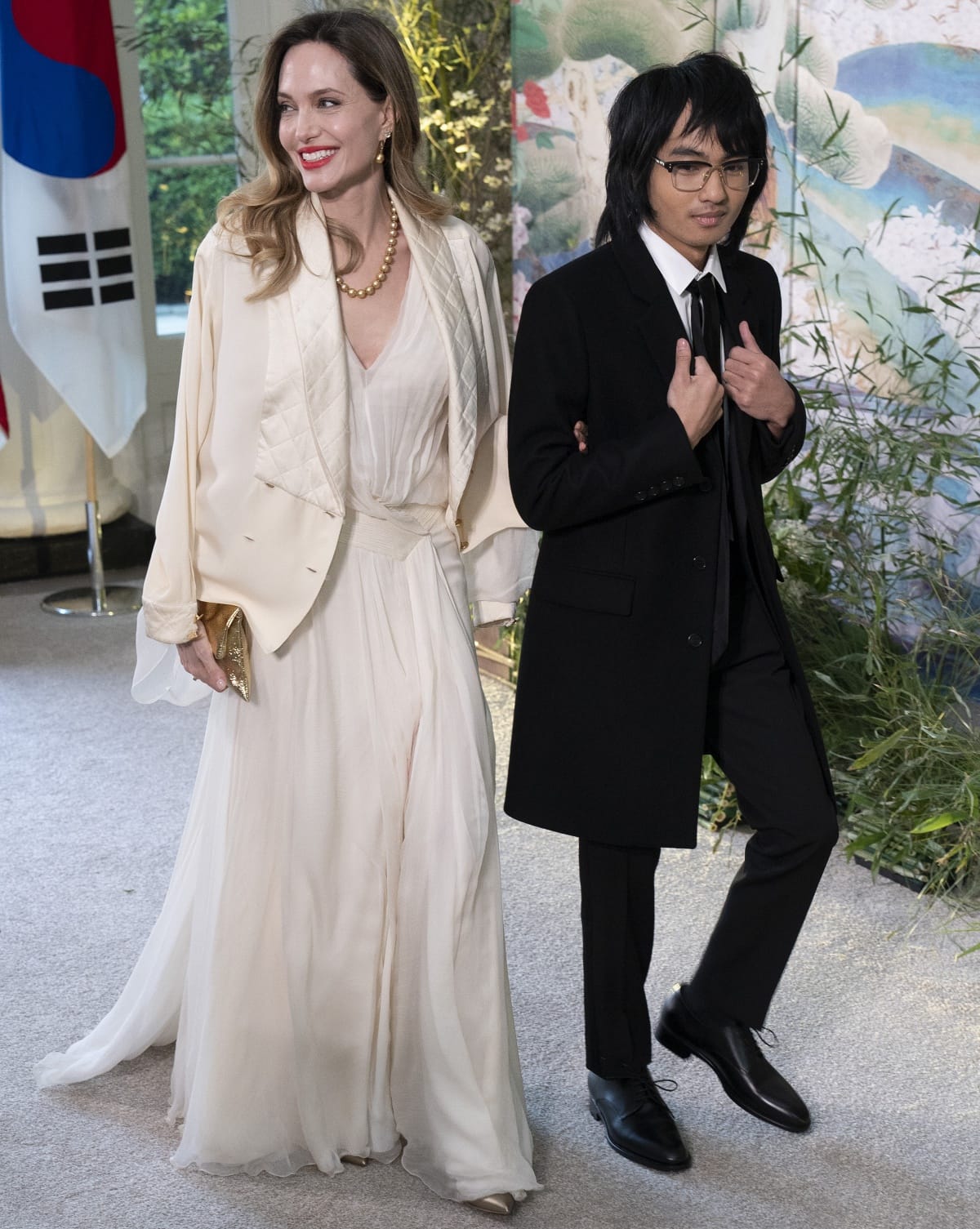 Angelina Jolie in a Chanel quilted jacket over an ivory dress and Maddox Jolie-Pitt in a classic black suit