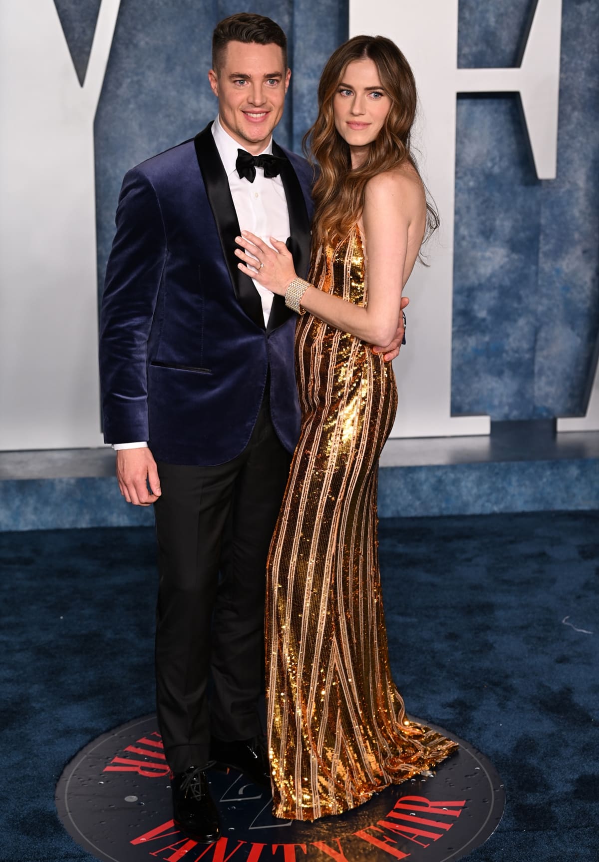 Allison Williams, in a mesmerizing gold gown by Galvan London gracefully complemented with exquisite Cartier Jewelry, with her fiancé Alexander Dreymon