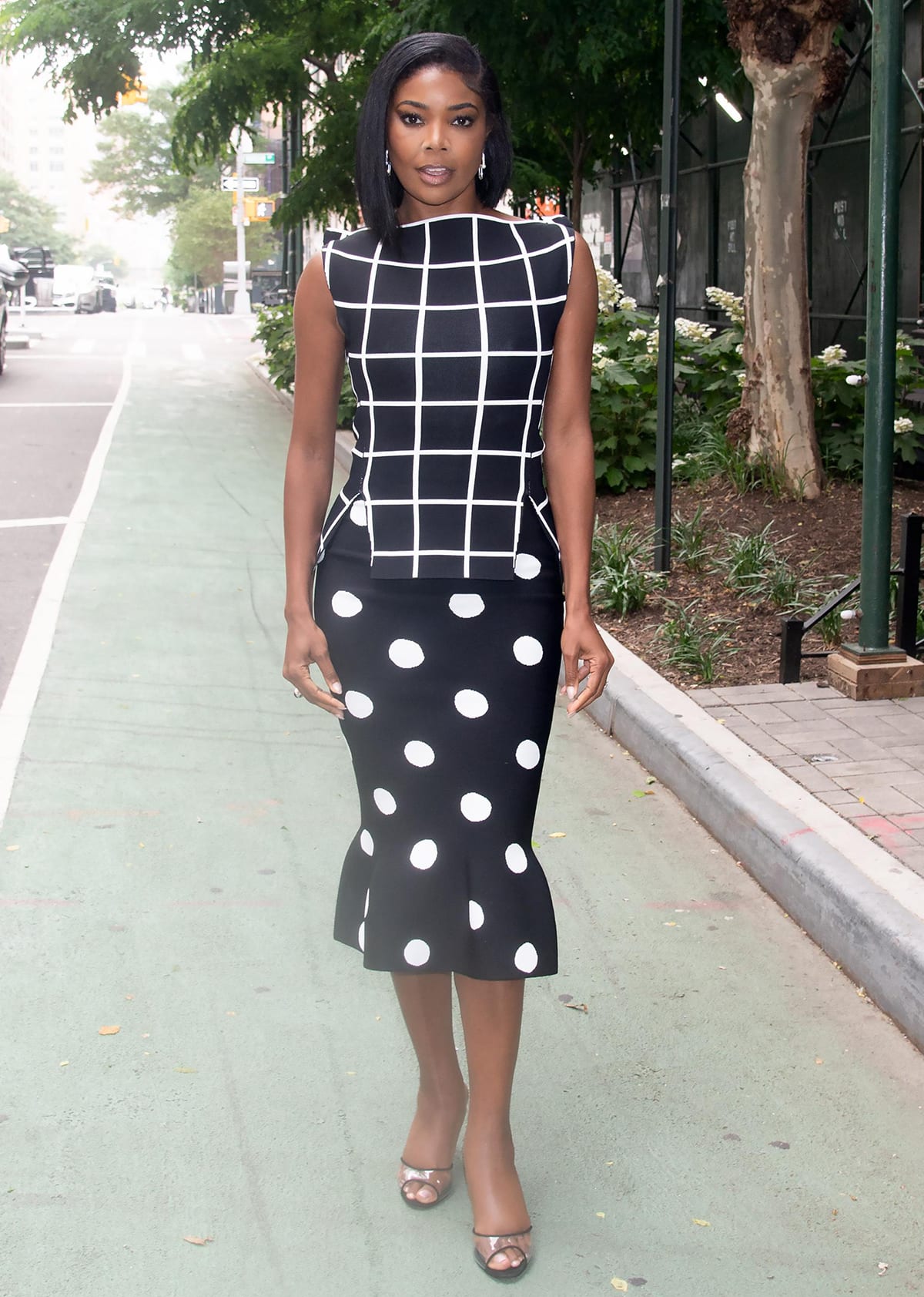 Gabrielle Union wears a mixed-pattern outfit composed of a checkerboard sleeveless top and a polka dot midi skirt to Watch Happens Live on June 12, 2023