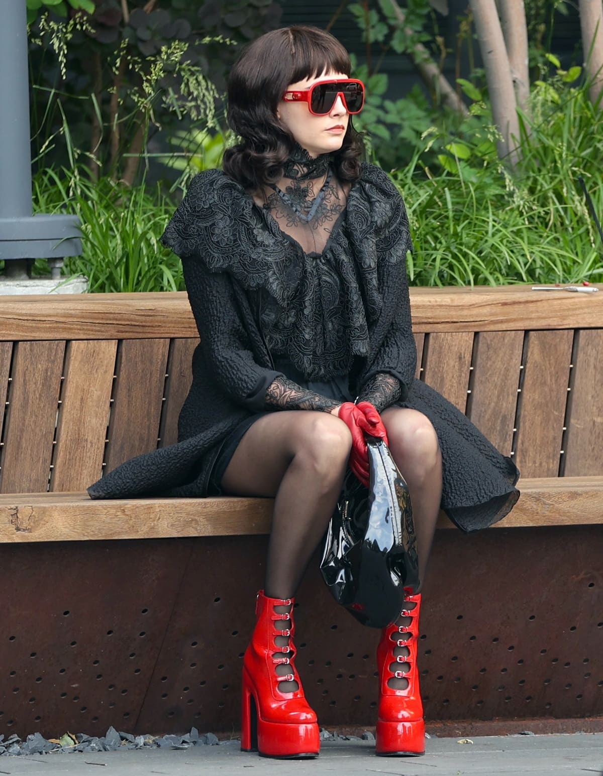 Cara Delevingne working on the set of American Horror Story's 12th season in New York City in a gothic black lace dress, a cloak, black stockings, and sky-high red patent leather heels
