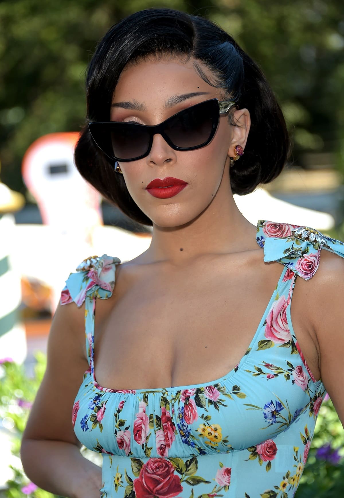 Doja Cat displays her boobs in a beautiful floral midi dress, complemented by cat-eye sunglasses during a Dolce & Gabbana event
