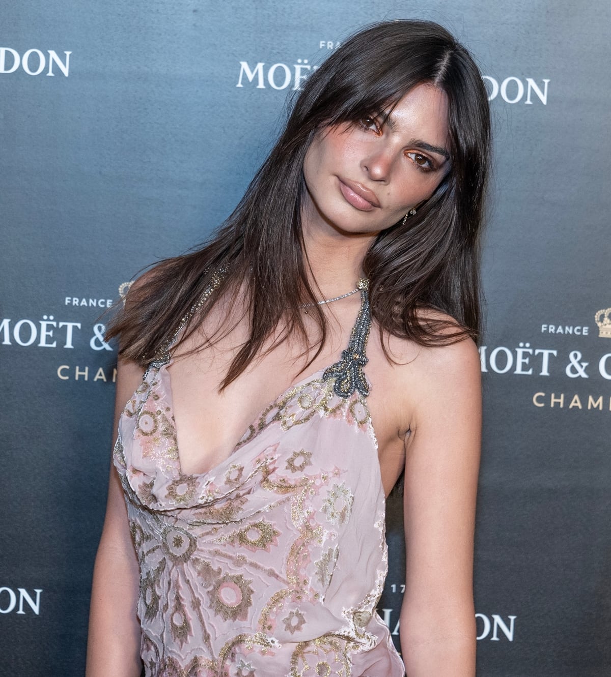 Emily Ratajkowski made a stylish entrance at the Moet and Chandon's Holiday Season Celebration in New York City in an eye-catching pink-and-burgundy satin dress