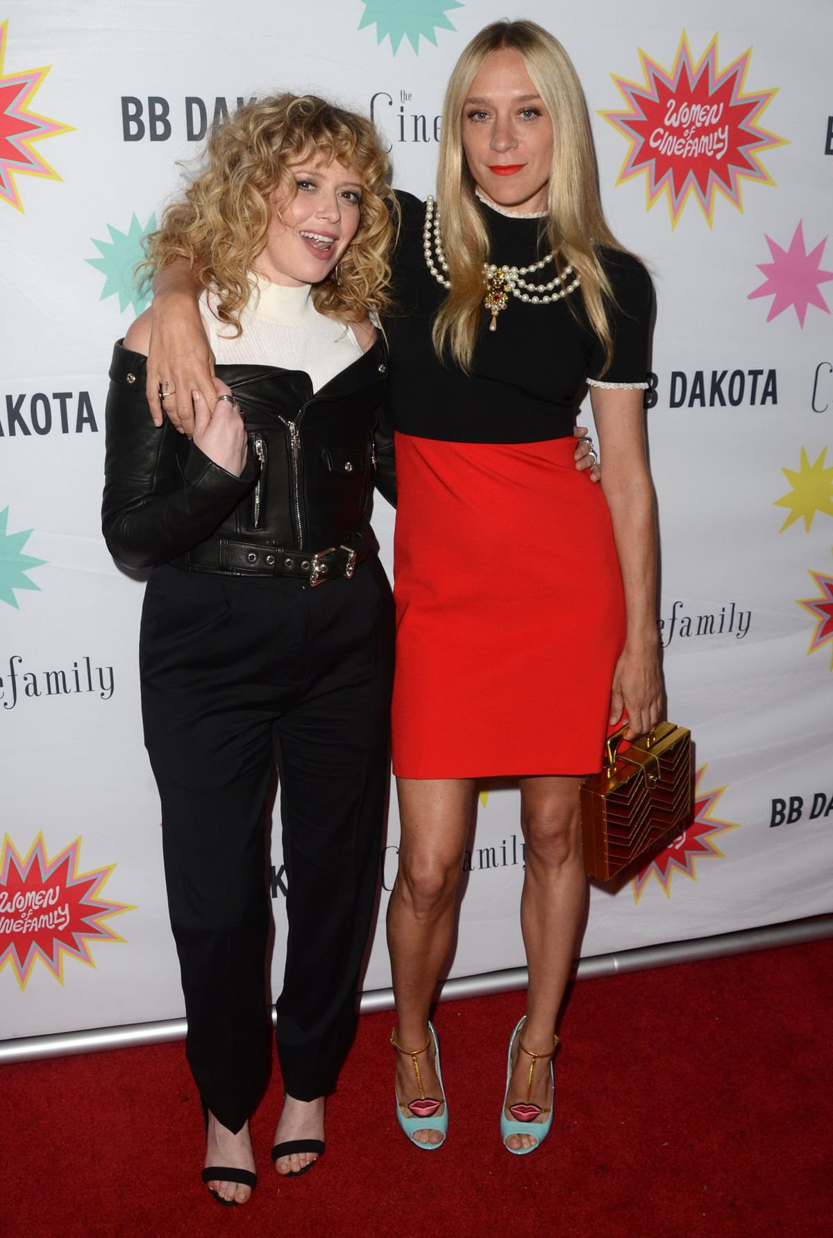 Natasha Lyonne and Chloë Sevigny pose together at the "Antibirth" premiere, showcasing their contrasting outfits and height difference