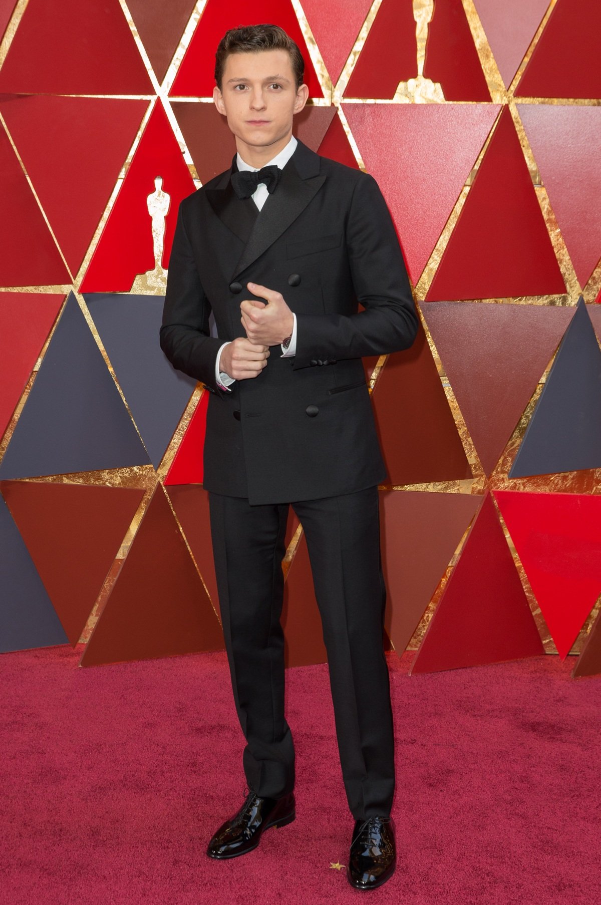 Tom Holland exudes timeless sophistication in a custom black Hermès double-breasted tuxedo and polished patent Oxford shoes at the 90th Academy Awards on March 4, 2018