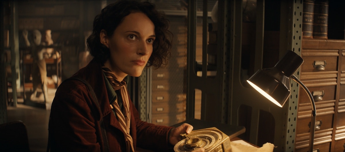 Phoebe Waller-Bridge as Helena Shaw carefully examines an ancient artifact in Indiana Jones and the Dial of Destiny, adding her unique flair to the iconic adventure series