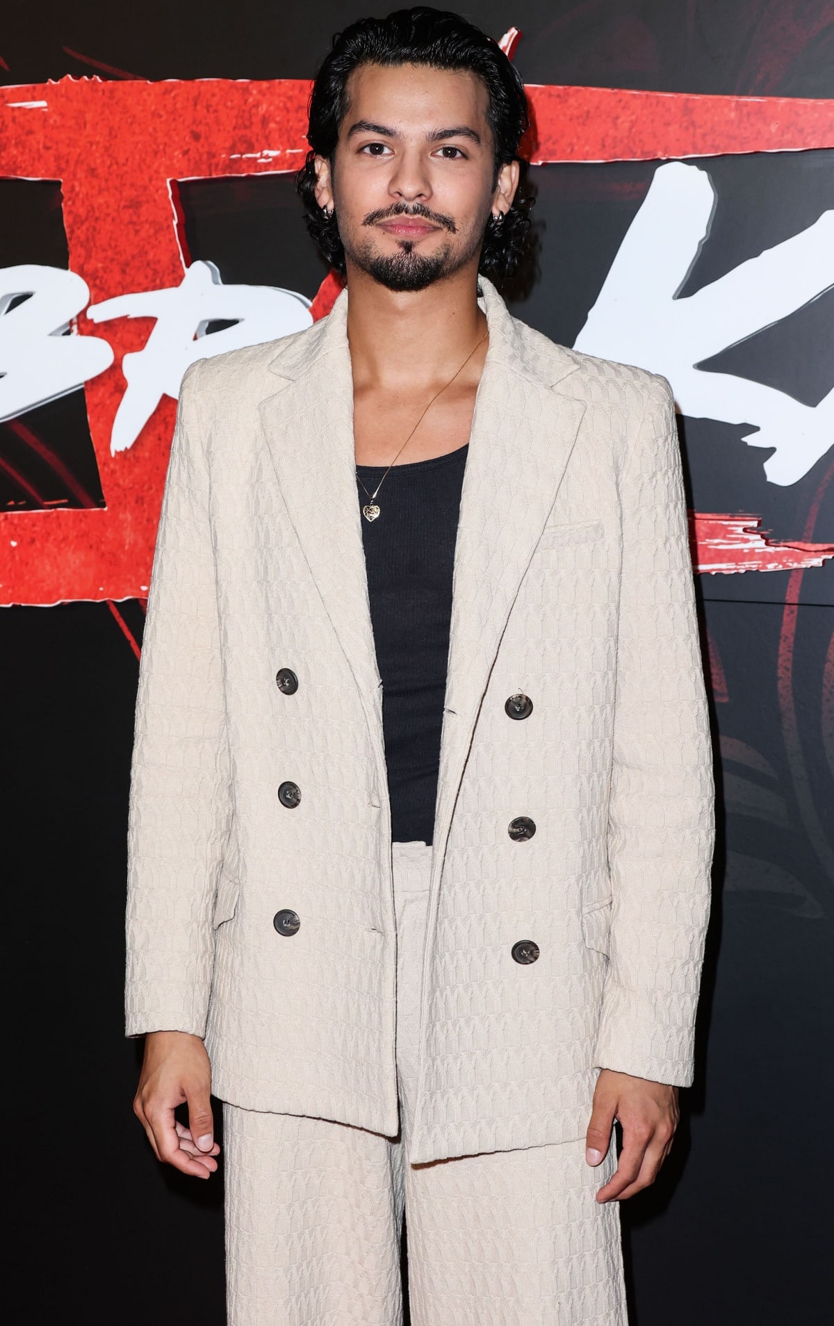 Xolo Maridueña attends a premiere in a textured cream suit paired with a black shirt, exuding effortless style and sophistication
