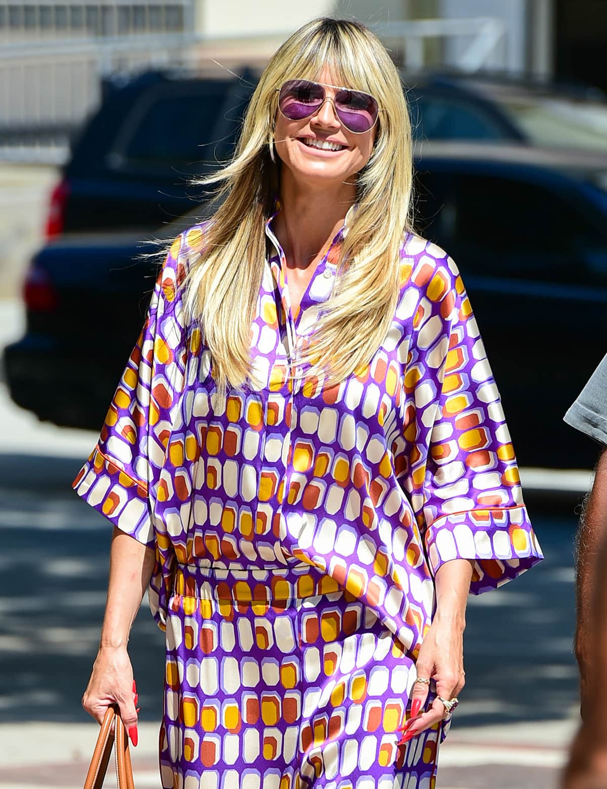 Heidi Klum keeps her look cohesive by wearing purple aviators and carrying a tan Hermes Birkin bag