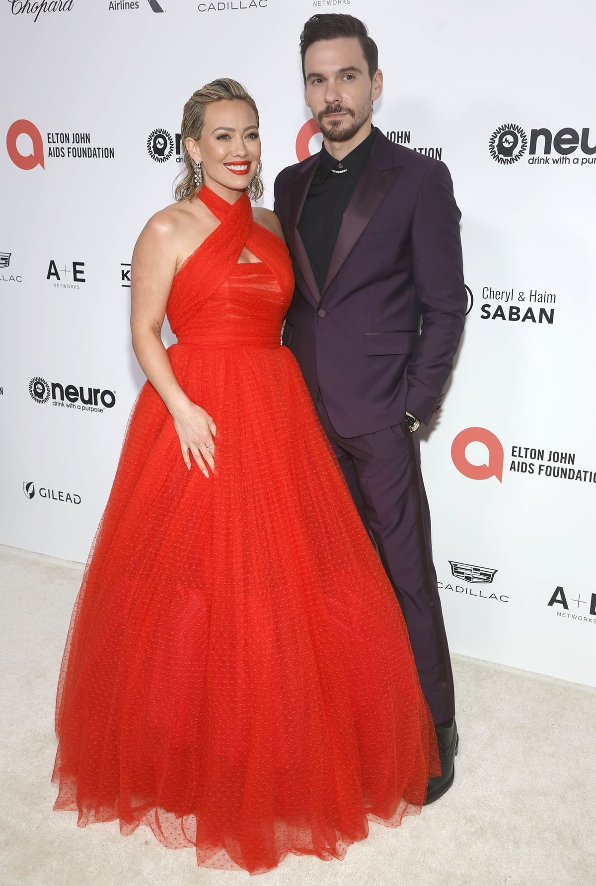 Hilary Duff, in a red Giambattista Valli ballgown with a halter neckline, posing with Matthew Koma at the Elton John AIDS Foundation's 31st Annual Academy Awards Viewing Party