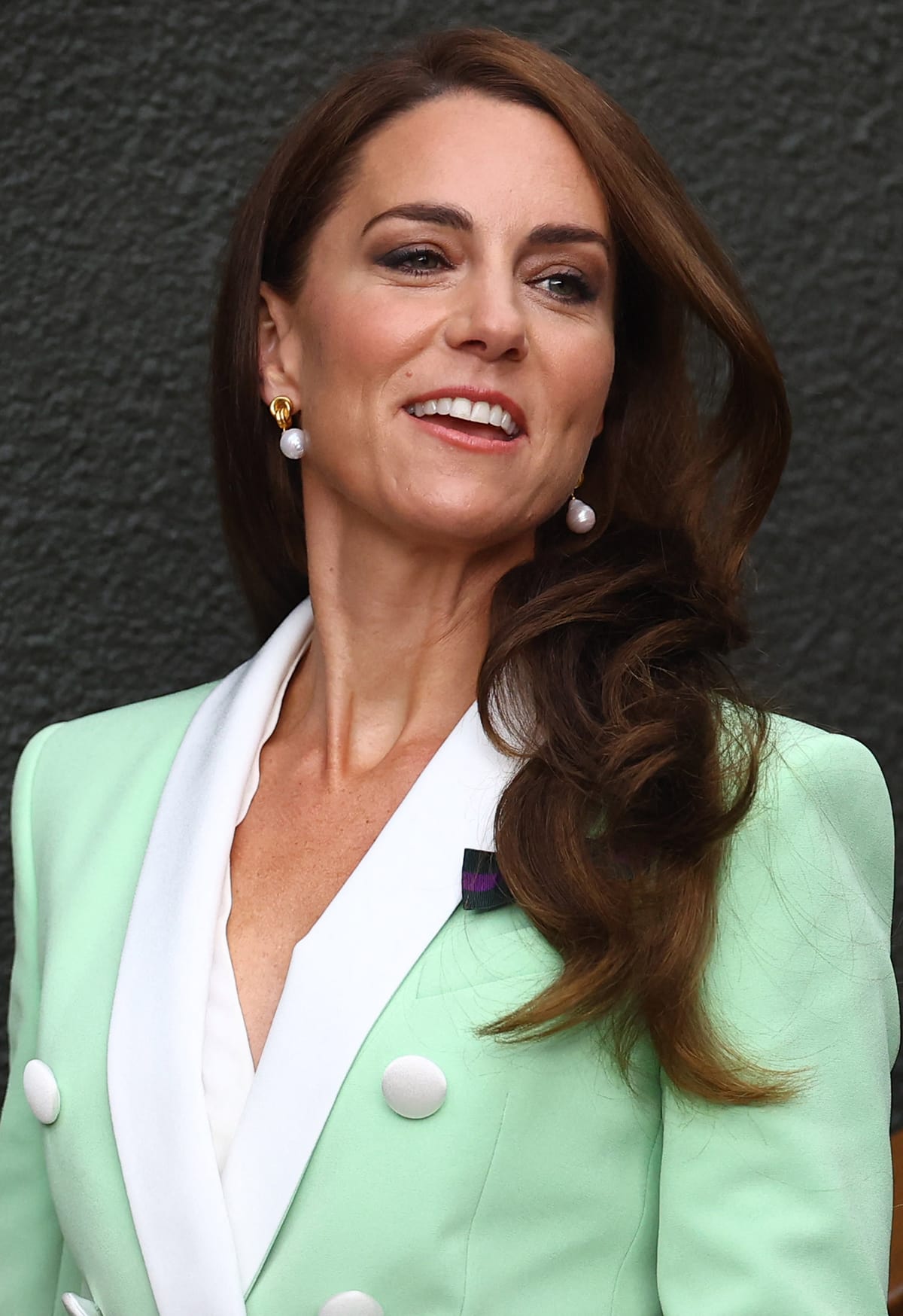 Kate Middleton enhances her beautiful features with brown smokey eyeshadow and red lipstick and styles her tresses in soft curls