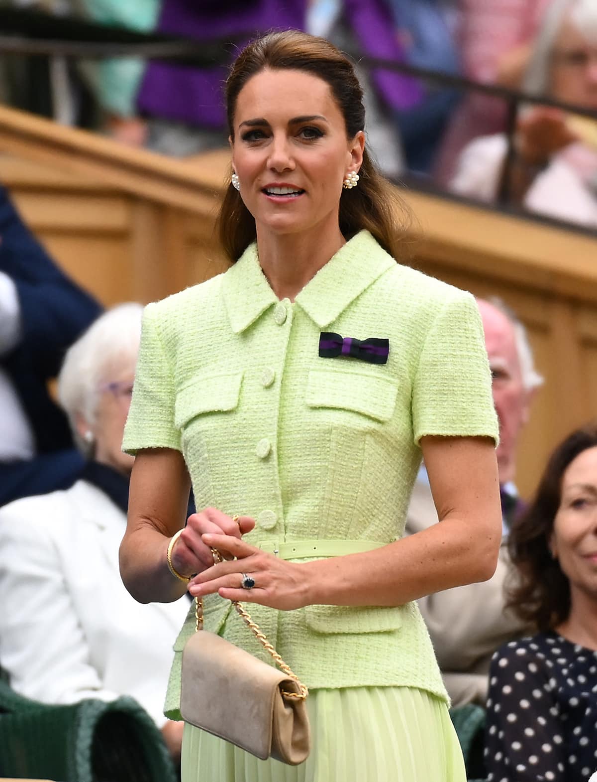 Kate Middleton carries a blush Emmy London purse and wears her hair in a half-up half-down style, showcasing her Cassandra Goad pearl cluster earrings